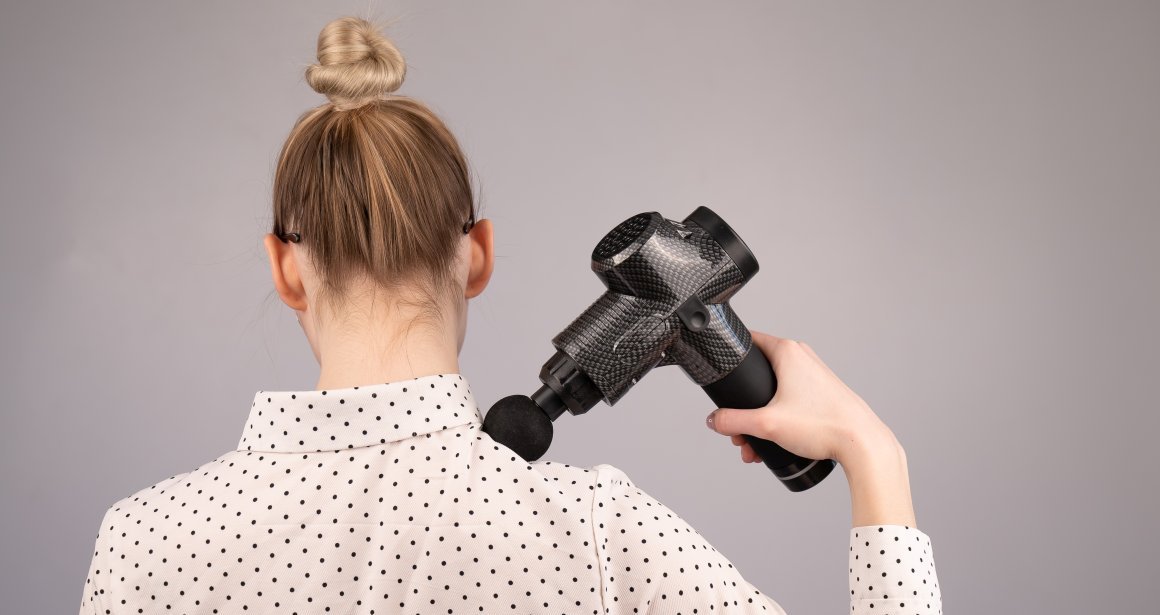 Woman using a massage gun on her neck